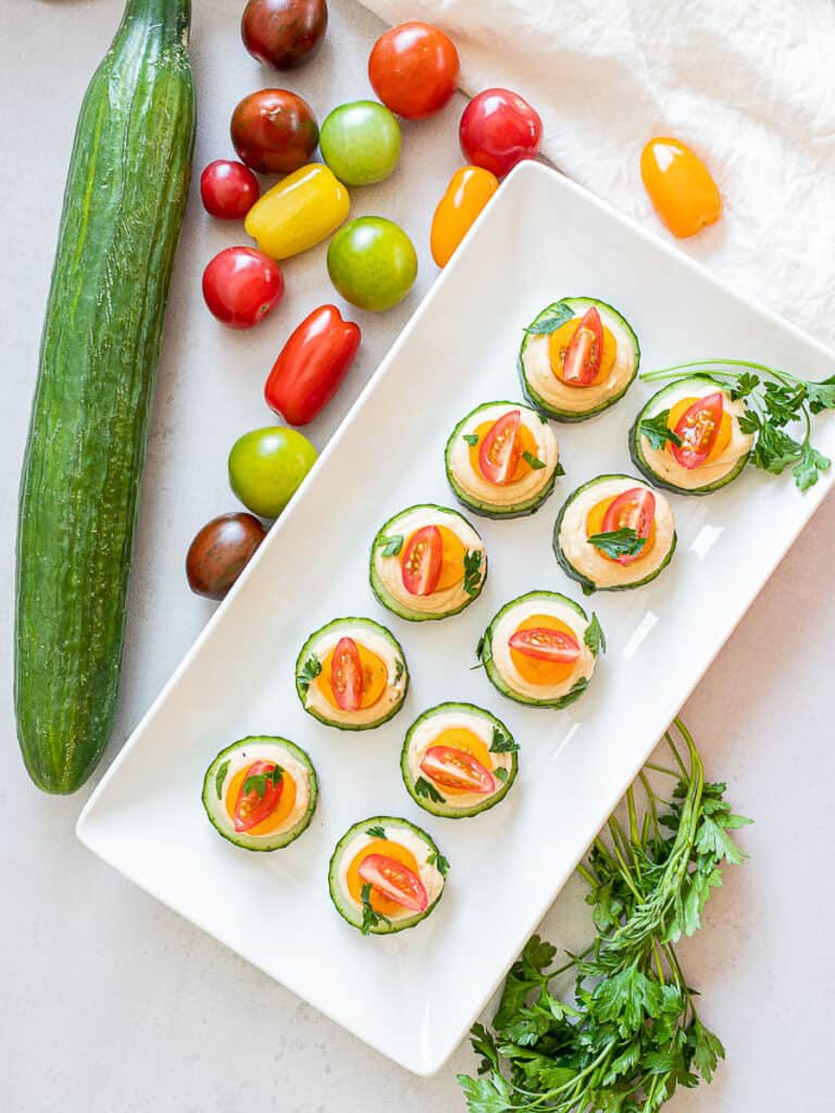 easy cold cucumber canapes on a plate with tomatoes on top