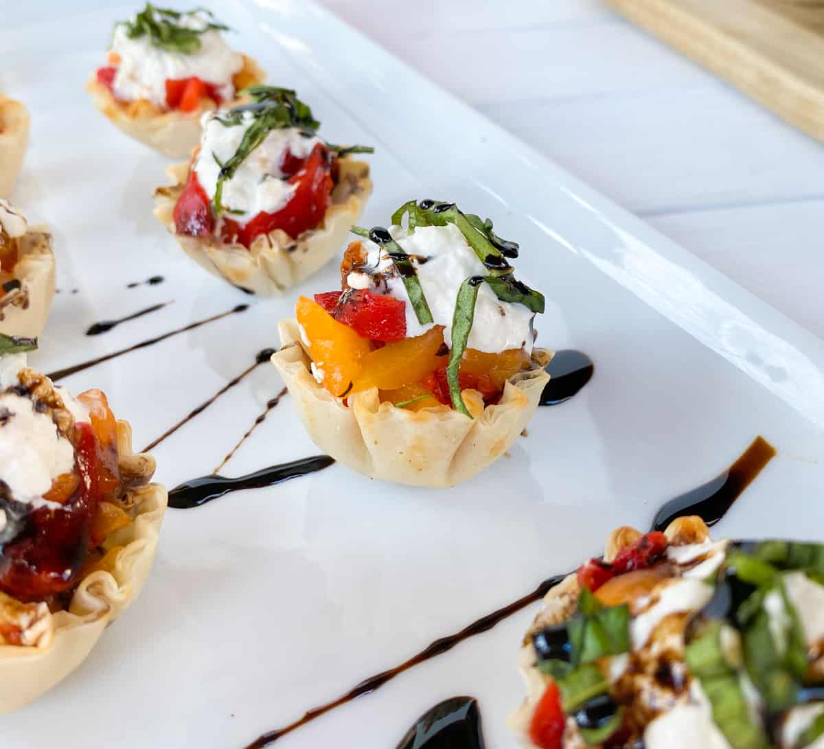 phyllo shells stuffed on a plate topped with balsamic vinegar.