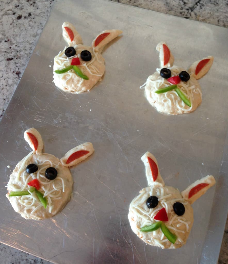 Easter bunny biscuit appetizers shaped into a head on a baking pan.