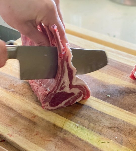 Showing how to french a rack of lamb into lollipops.