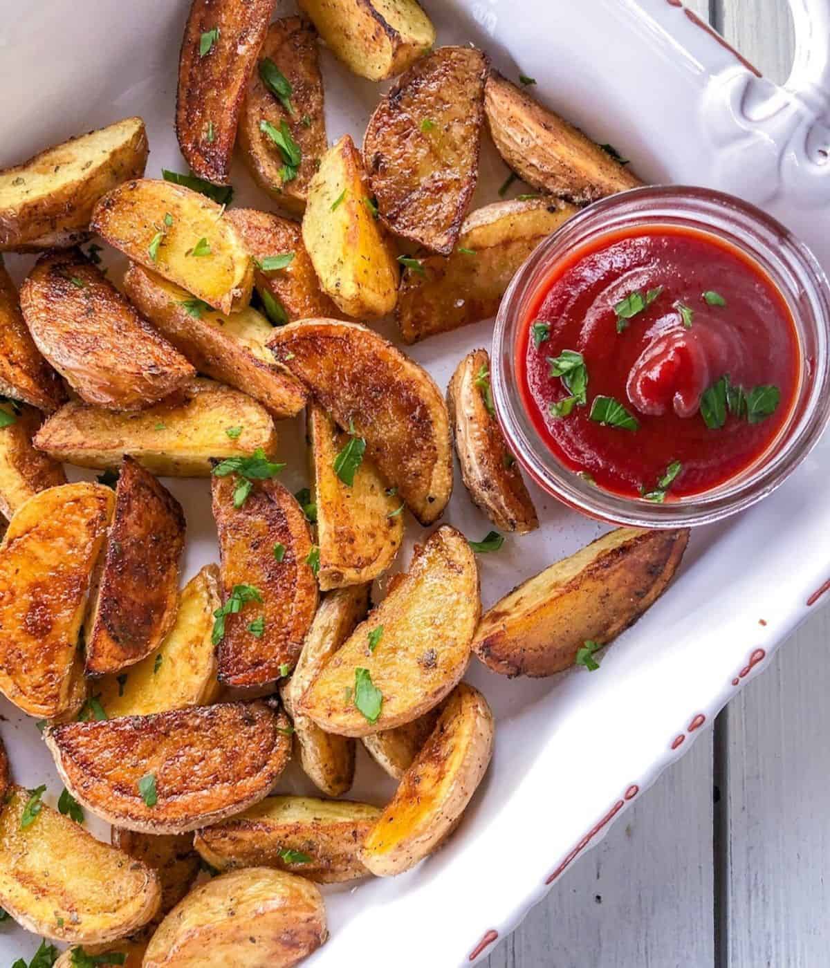 Crispy oven roasted potato wedges on plate with ketchup.