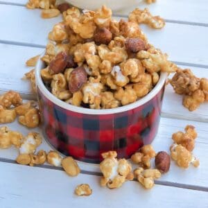 caramel popcorn and nuts in a red small bowl.