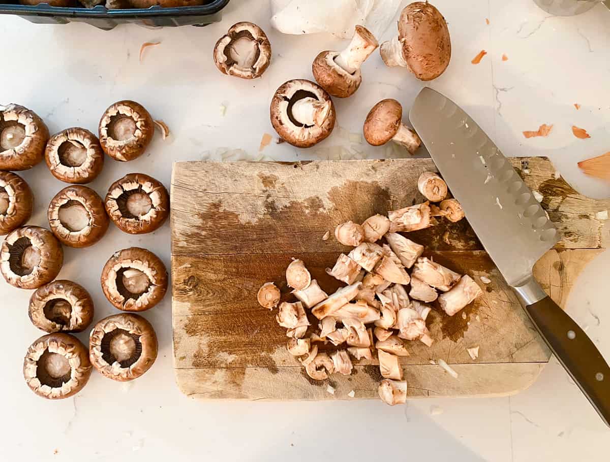 Mushrooms on a cutting board with a knife.