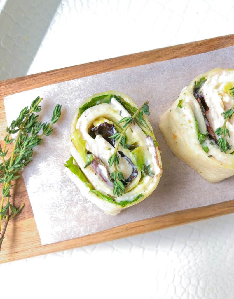 turkey avocado and cheese tortilla cut into slices on a cutting board with thyme garnish