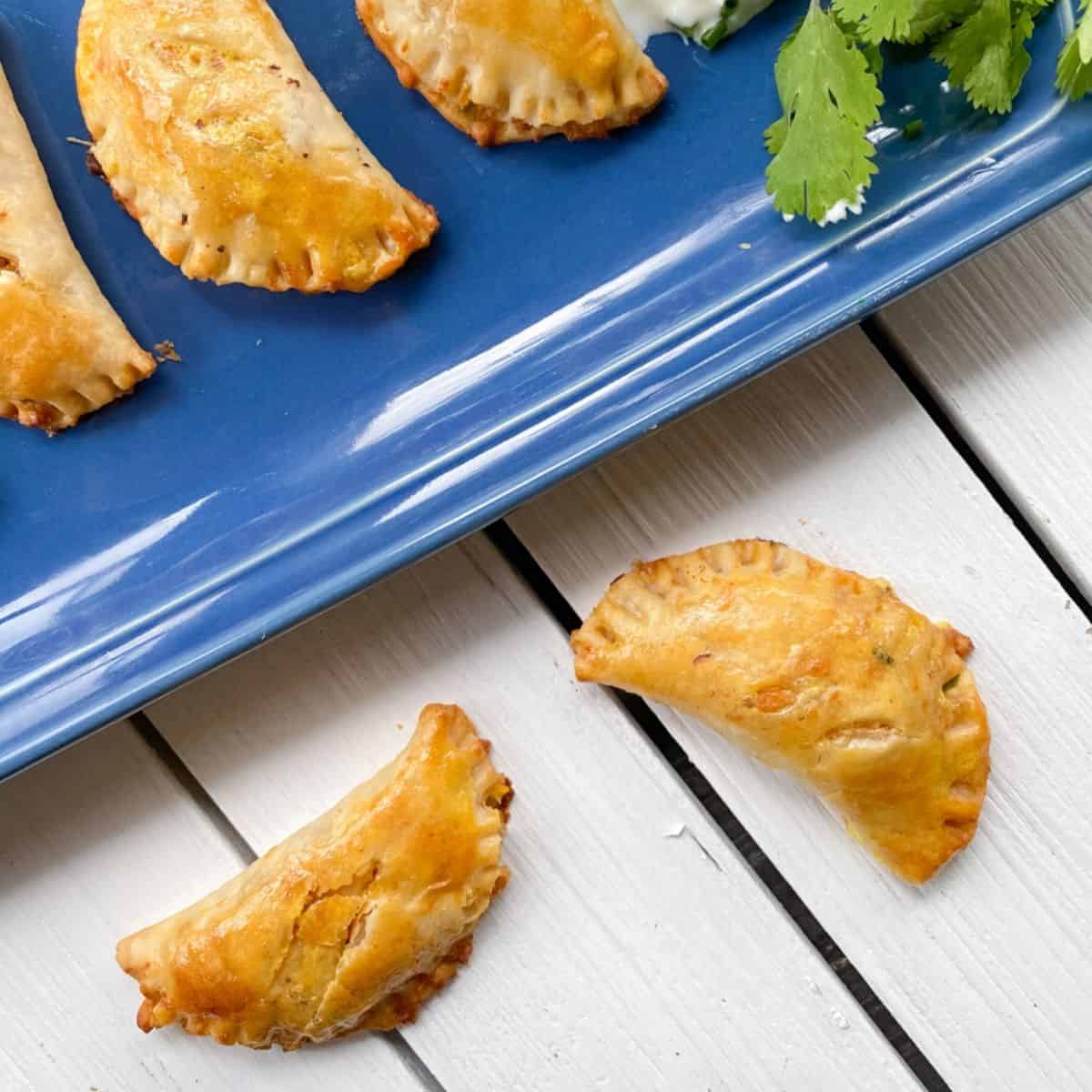 vegetarian empanadas on a blue plate and white table.