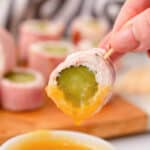 Pickle ham roll up dunked into sauce.