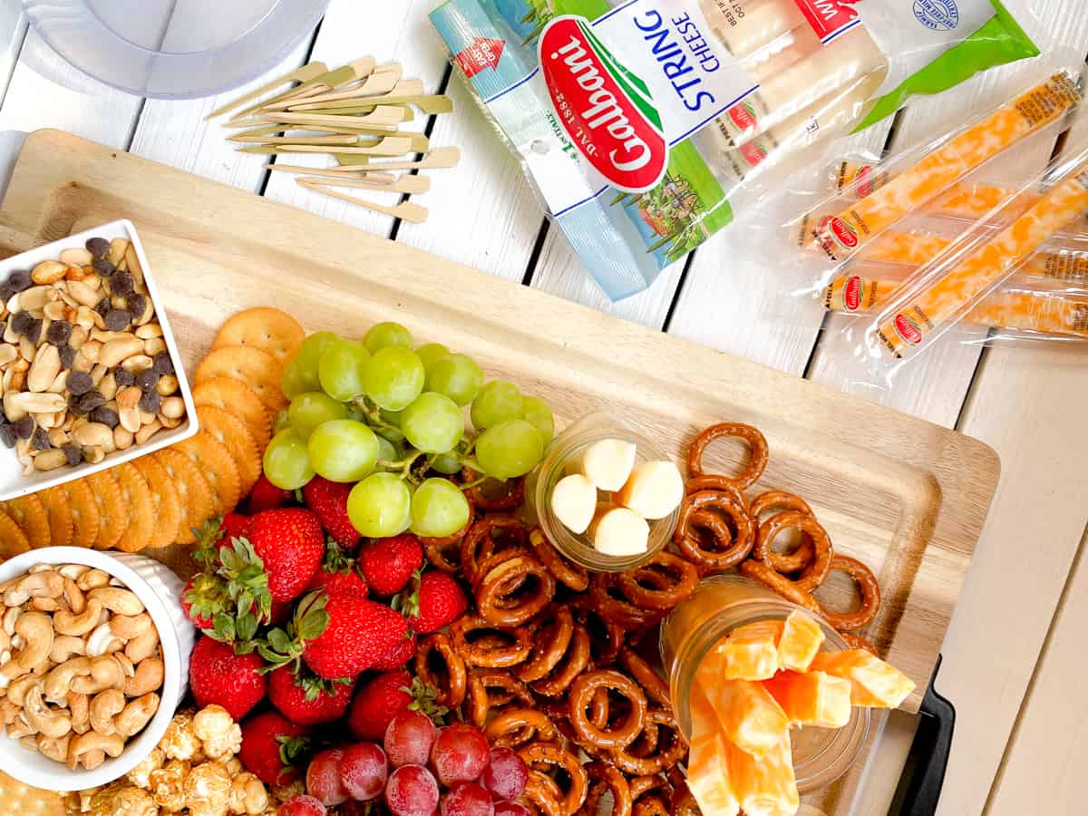 kid friendly charcuterie board with pretzels, nuts, cheeses and fruit.