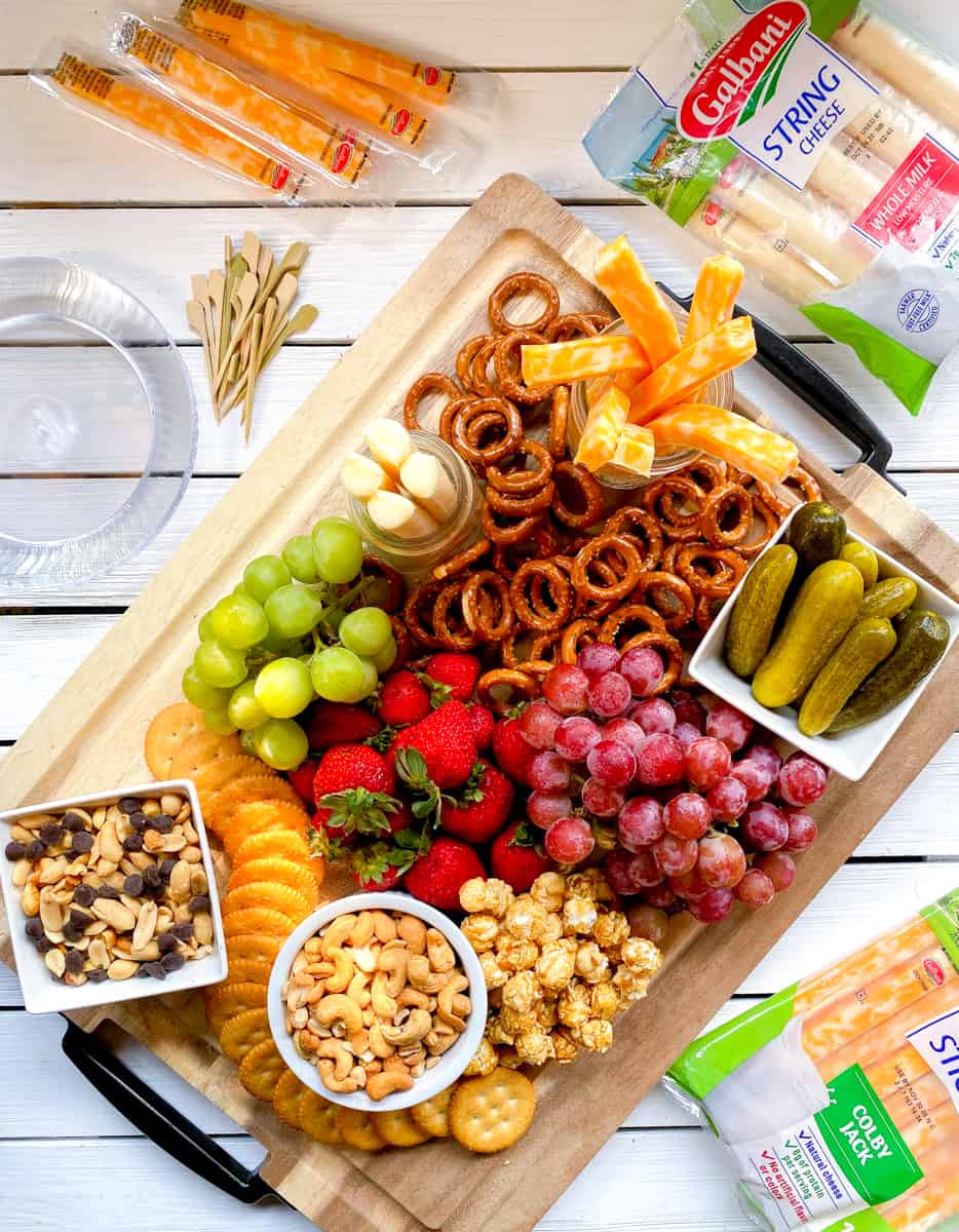 Kds snack board with cheese, fruit, snacks and nuts.