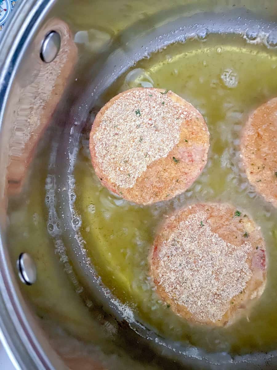 Breaded tomatoes frying in hot oil.