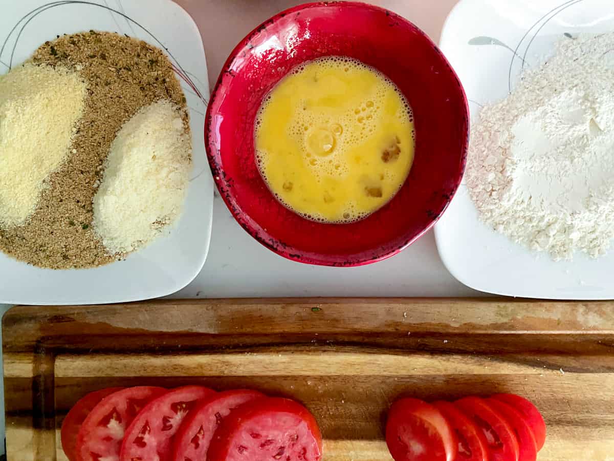 Fried tomato breading station with flour, cornmeal, breadcrumbs and eggs.