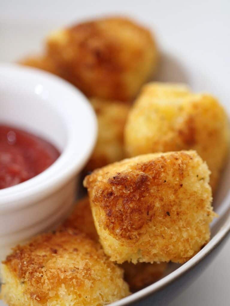 mac and cheese bites in a bowl with ketchup on the side.