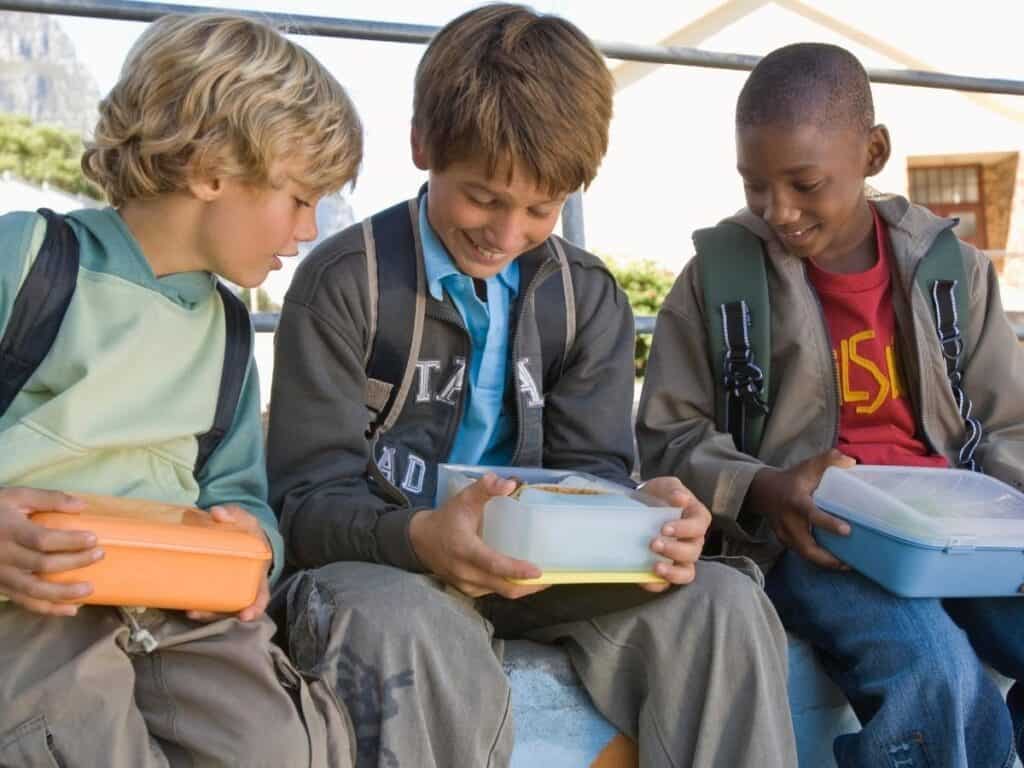 3 kids holding their lunch boxes