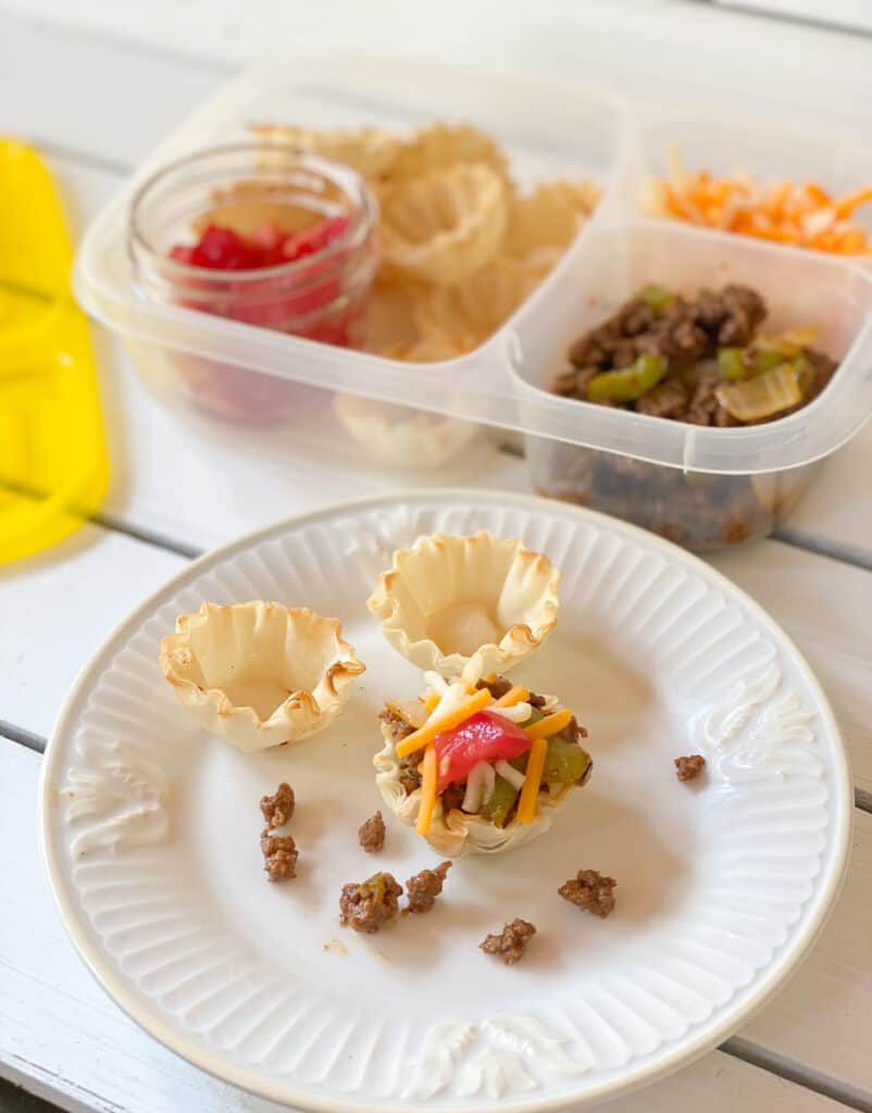 phyllo cups filled with ground meat tomatoes and cheese on a plate