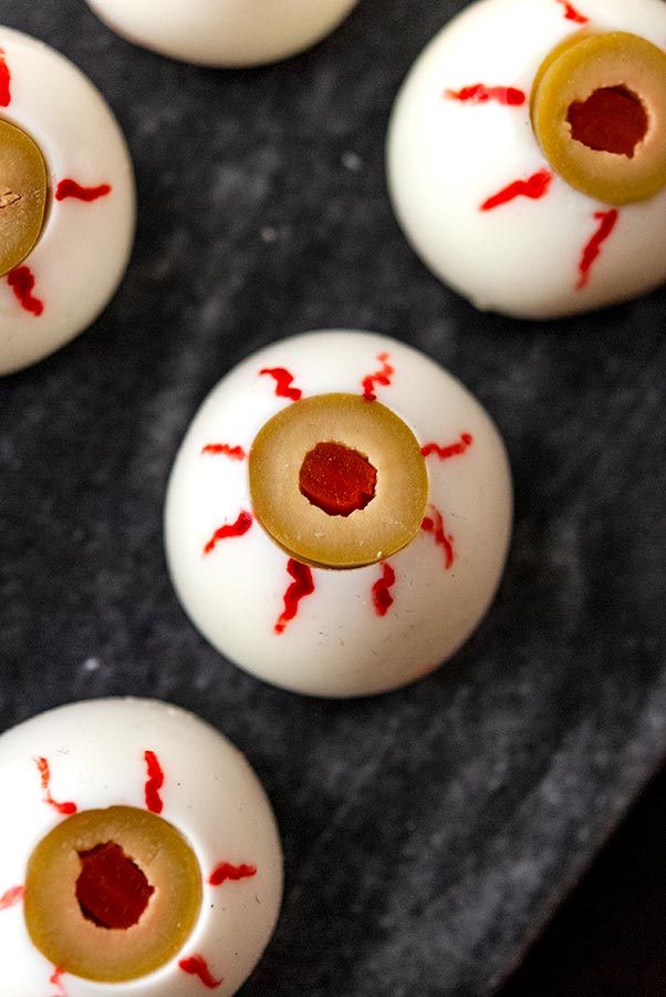 Halloween creepy deviled eggs appetizer turned into eyeballs with olives as eyes.