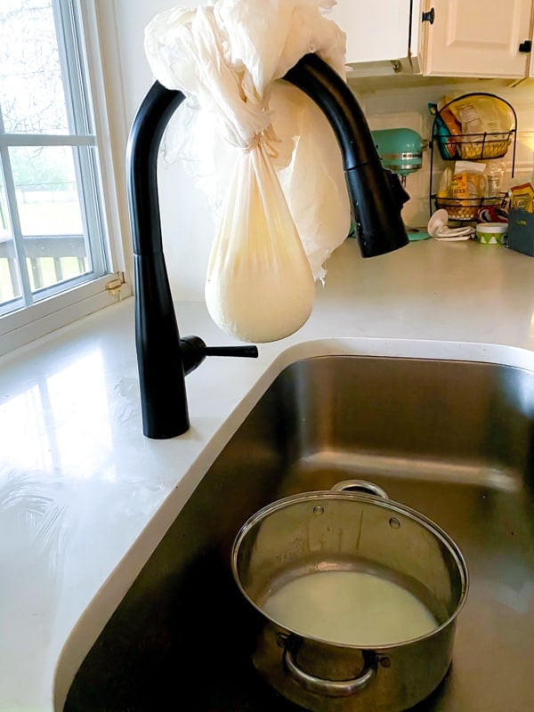 Cheese cloth filled with plain yogurt straining over a sink.