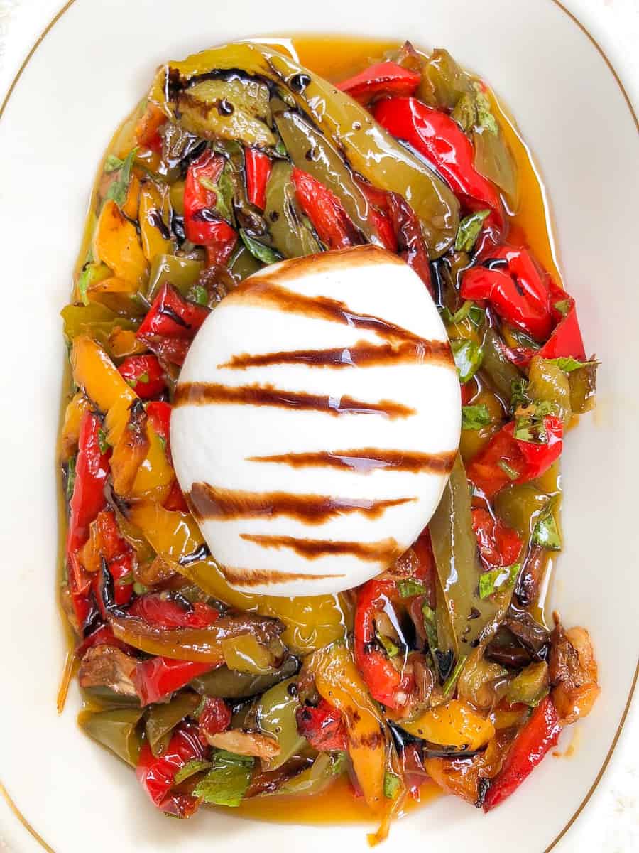 Burrata cheese with balsamic glaze over roasted red, yellow and green peppers.