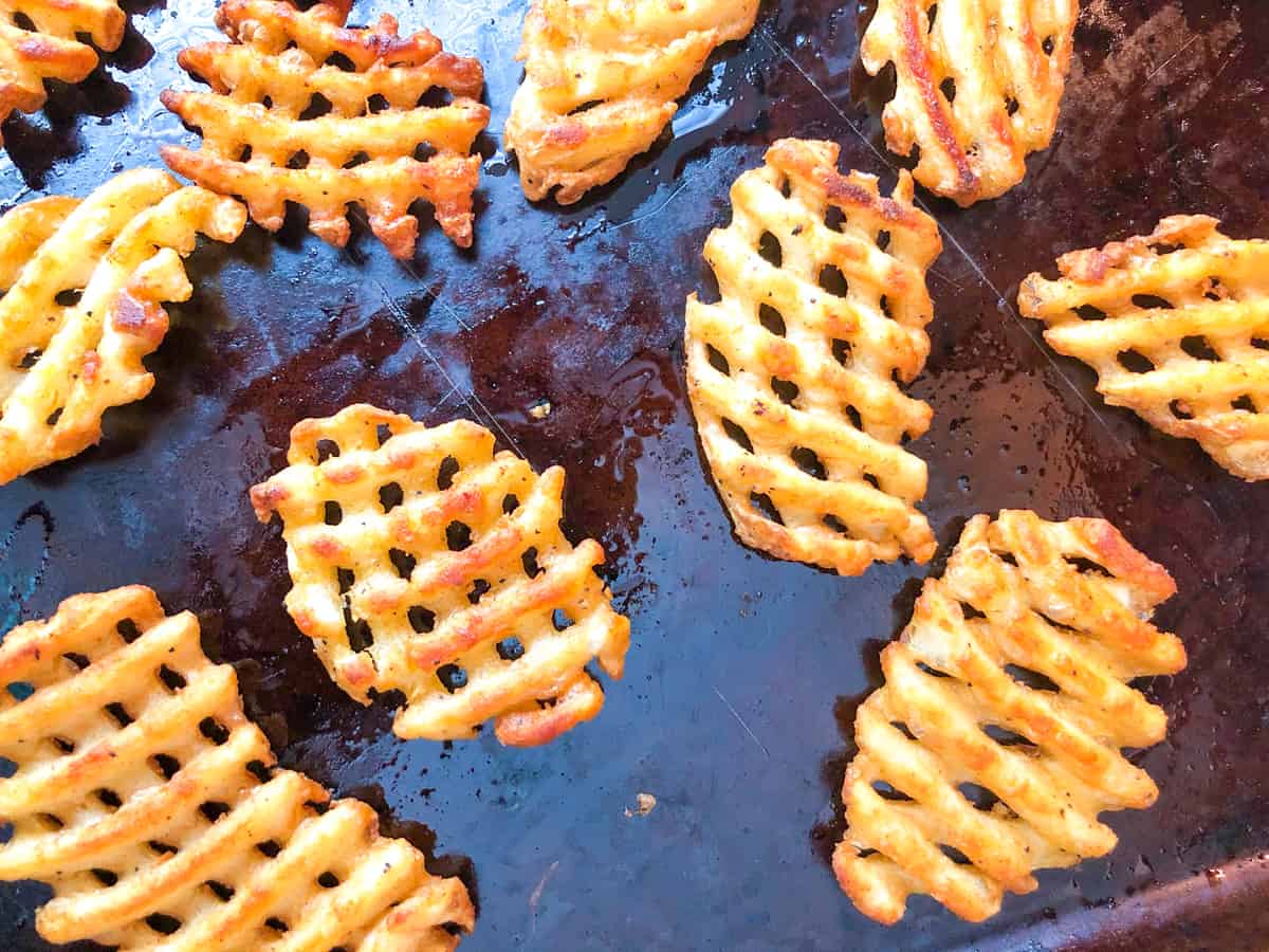 Baked waffle fries on a baking sheet.