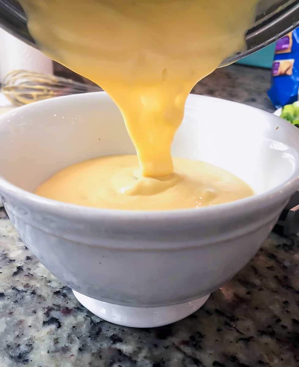 Homemade cheese sauce being poured into a bowl.