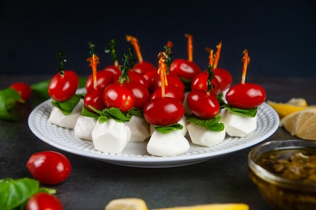 mini caprese appetizer skewers on a white plate.