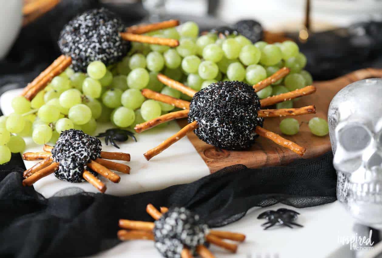 Cheeseballs coated in sesame seeds with pretzel sticks as legs to look like spiders.
