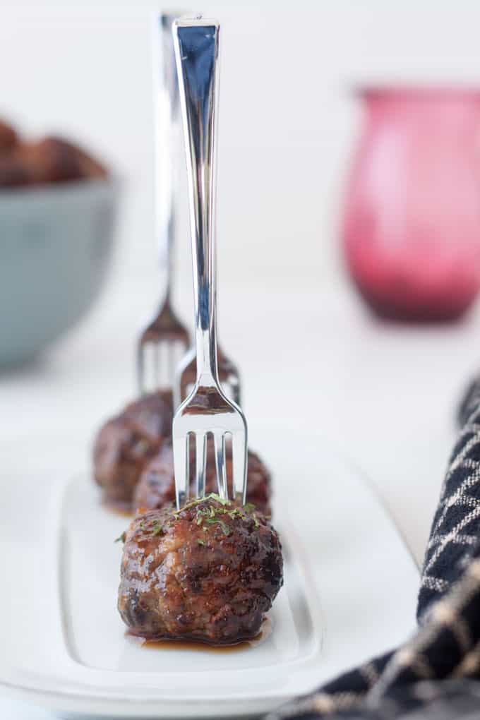 meatball skewers served with mini plastic forks on a plate.
