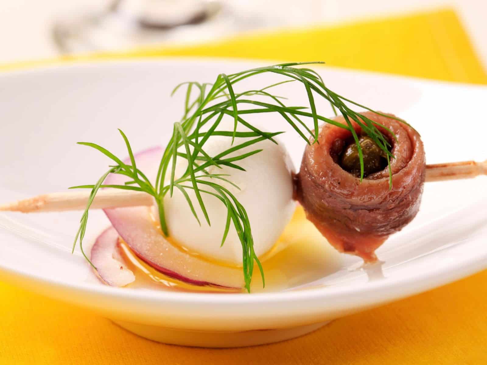 Amuse bouche on a toothpick with anchovy and quail egg.