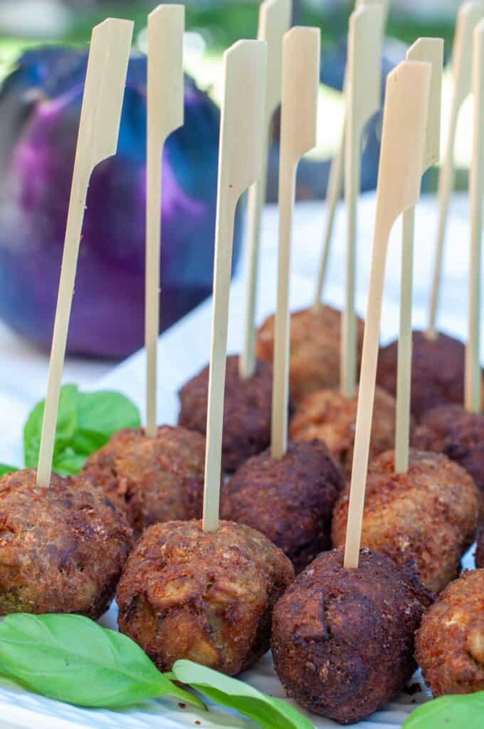 fried eggplant balls skewered and served on a plate.