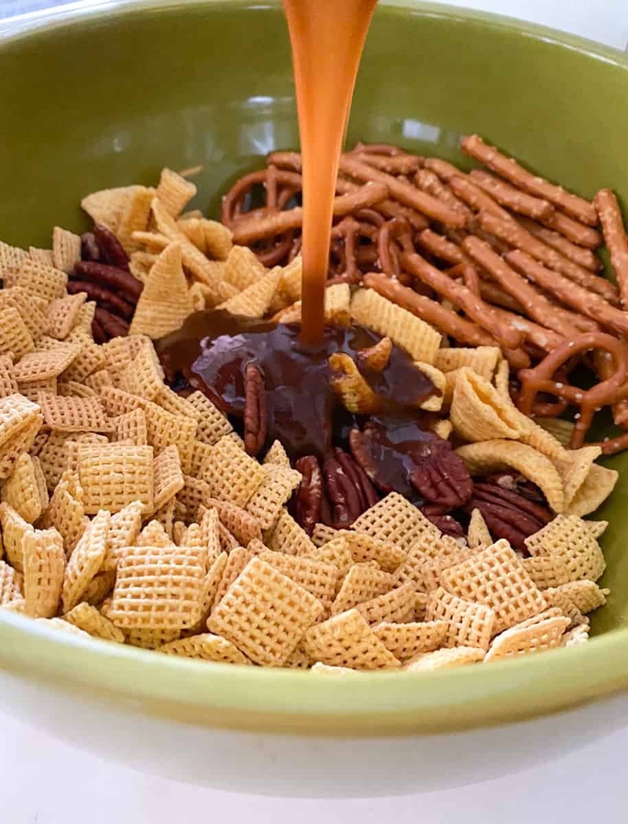 Chex mix in a bowl being poured with a brown sugar pumpkin spice glaze.