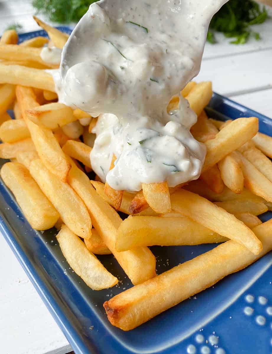 drizzling feta cheese sauce over french fries.