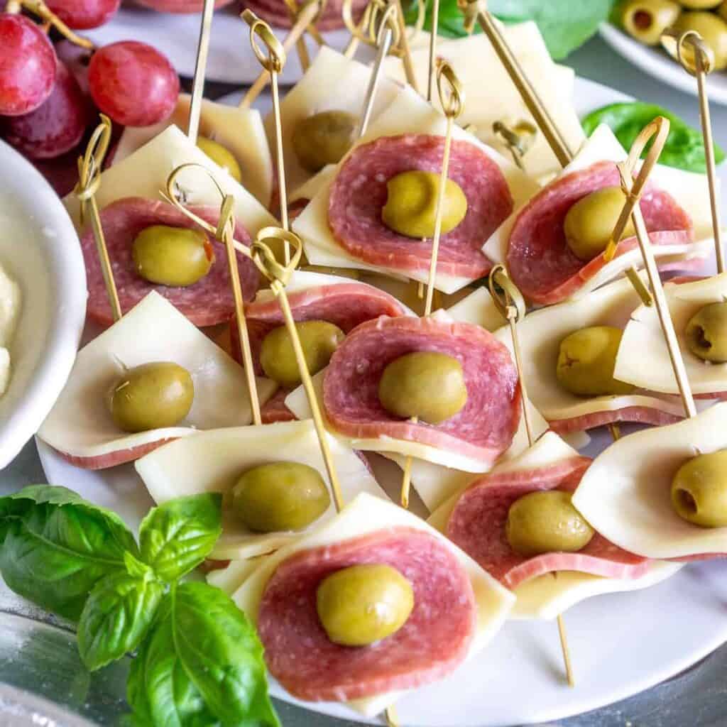 easy salami appetizer skewers on a plate with cheese and olives.