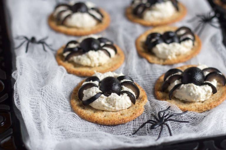Spooky crackers with cheese are topped with olives to resemble spiders
