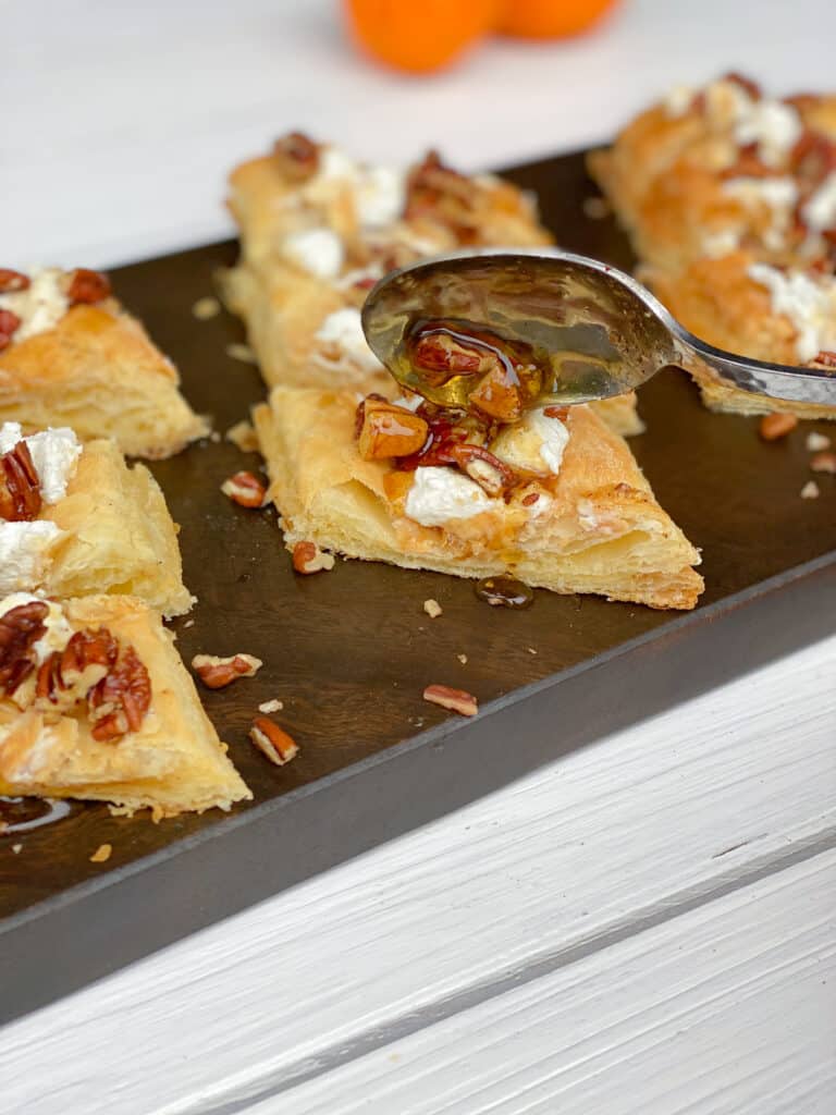 spooning maple pecan mixture over top of goat cheese puff pastry