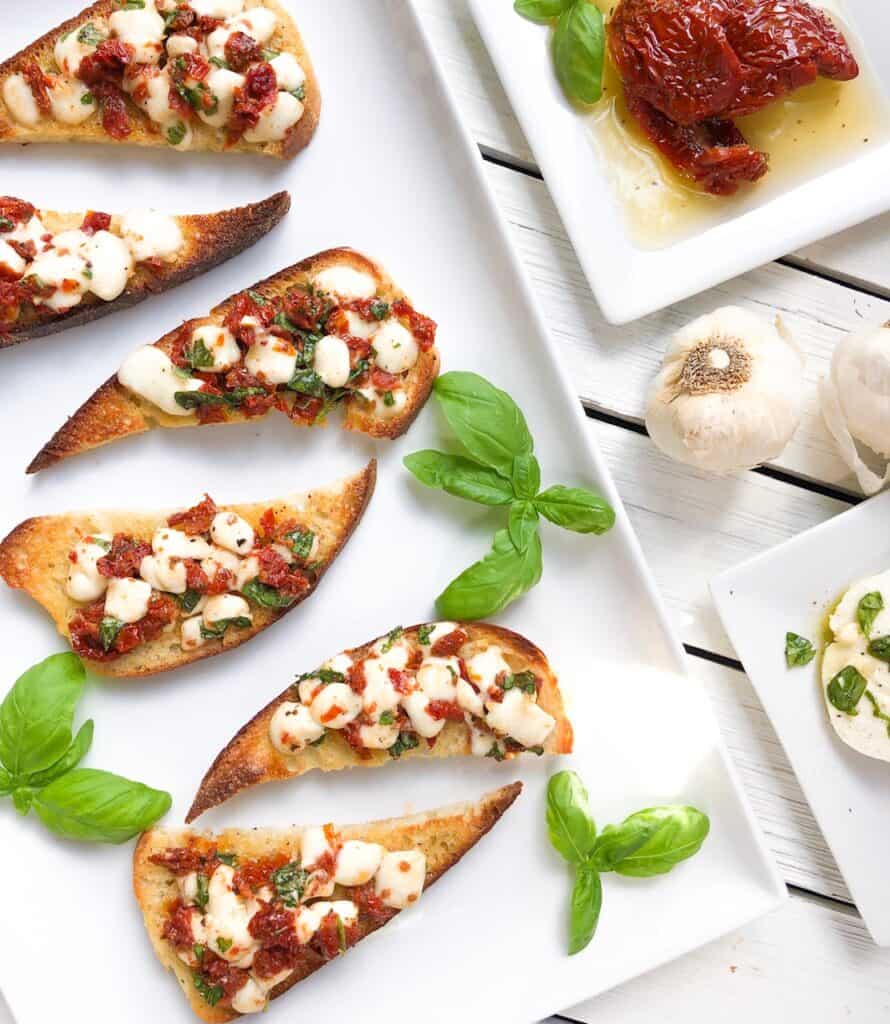 bruschetta caprese with sun dried tomatoes on plate with basil and garlic