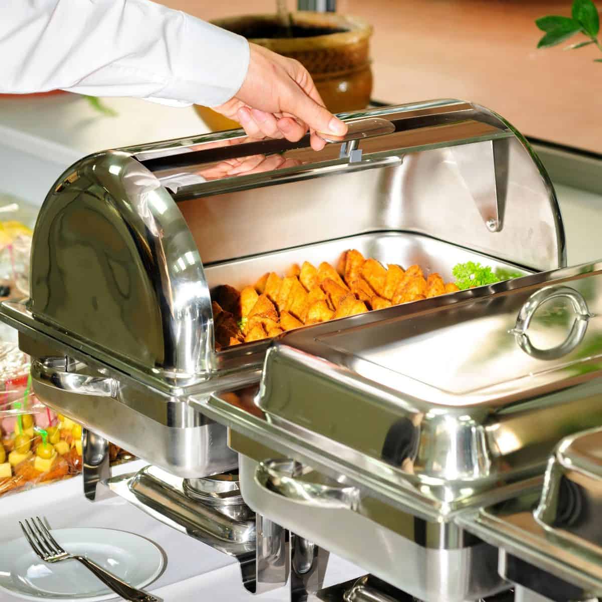 hand opening chafing dish at buffet table.