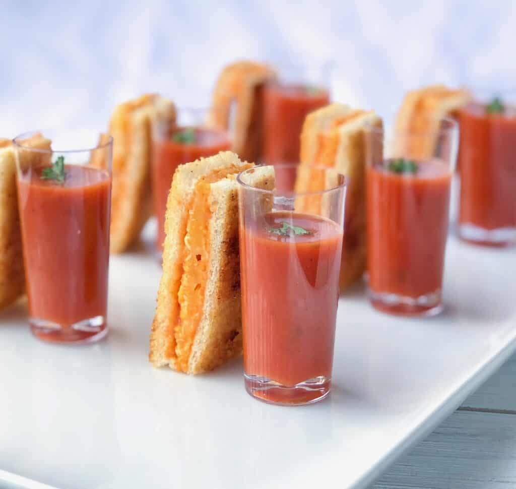 grilled cheese sticks with tomato soup hors d'oeuvre shooters on a white plate.