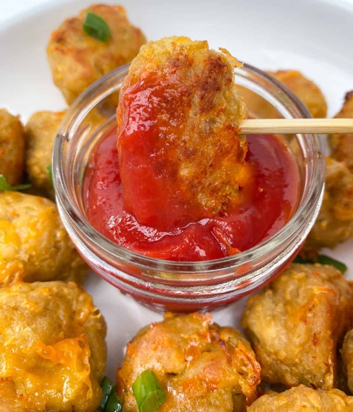 Sausage ball close up with ketchup on skewer.