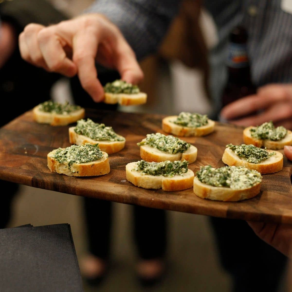 someone grabbing an appetizer off of a serving platter at a party.