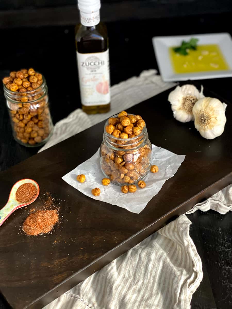 roasted chickpeas in a mason jar with spices and garlic around.