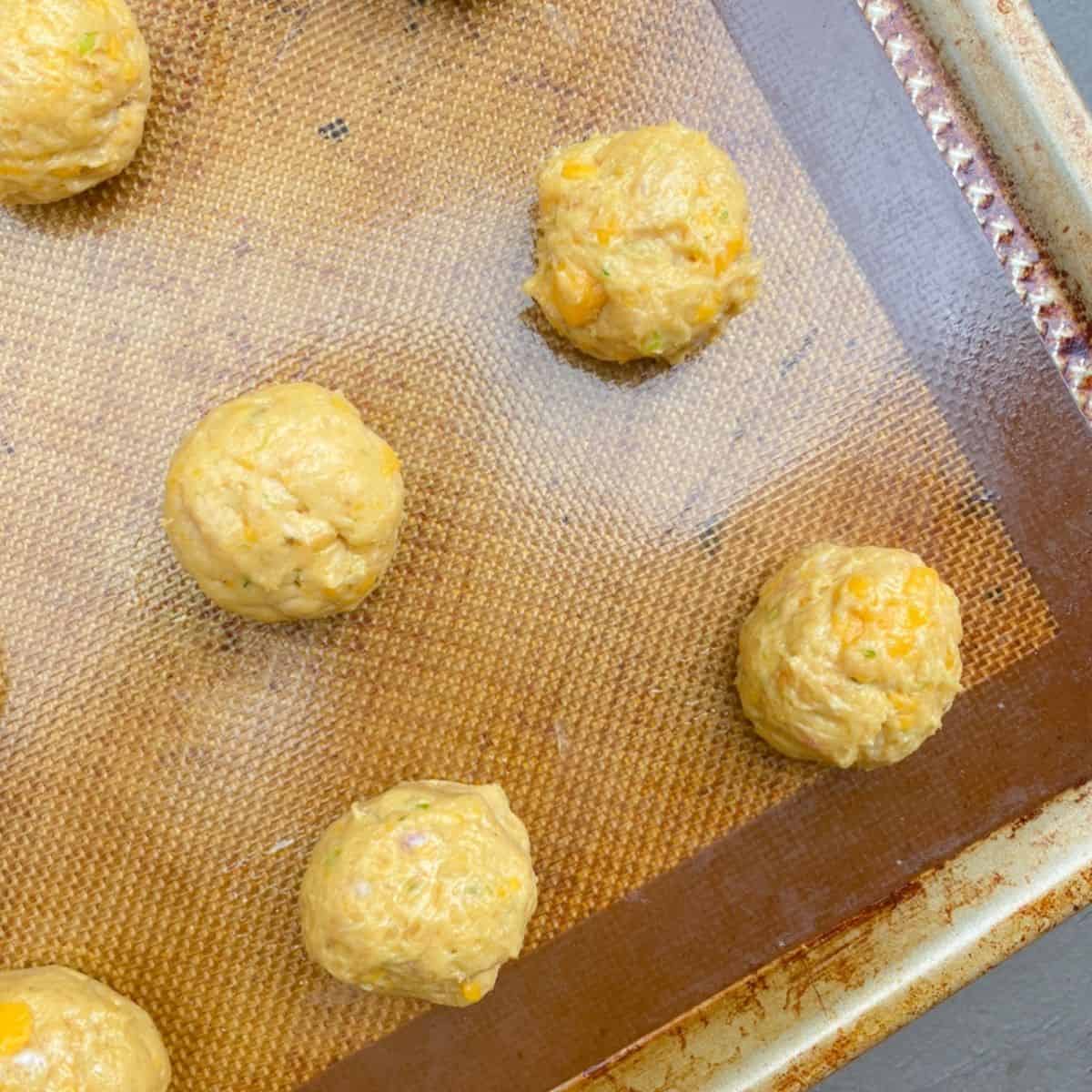 Sausage balls rolled on nonstick baking sheet ready to bake.