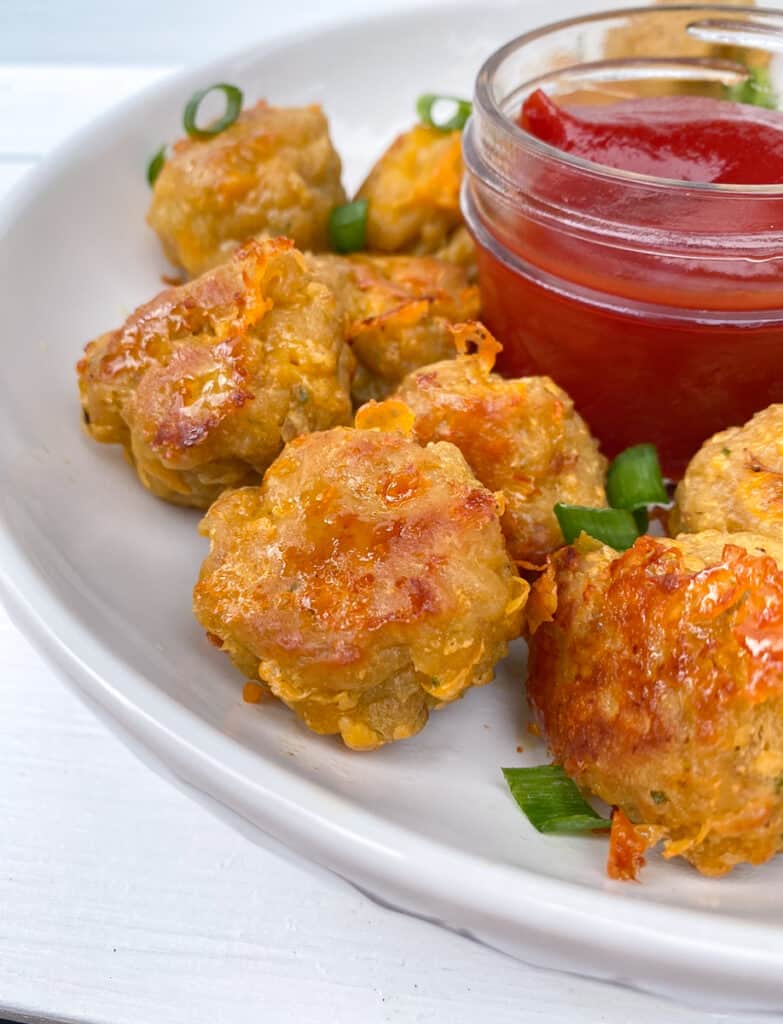 Sausage balls on a plate around ketchup for dipping.