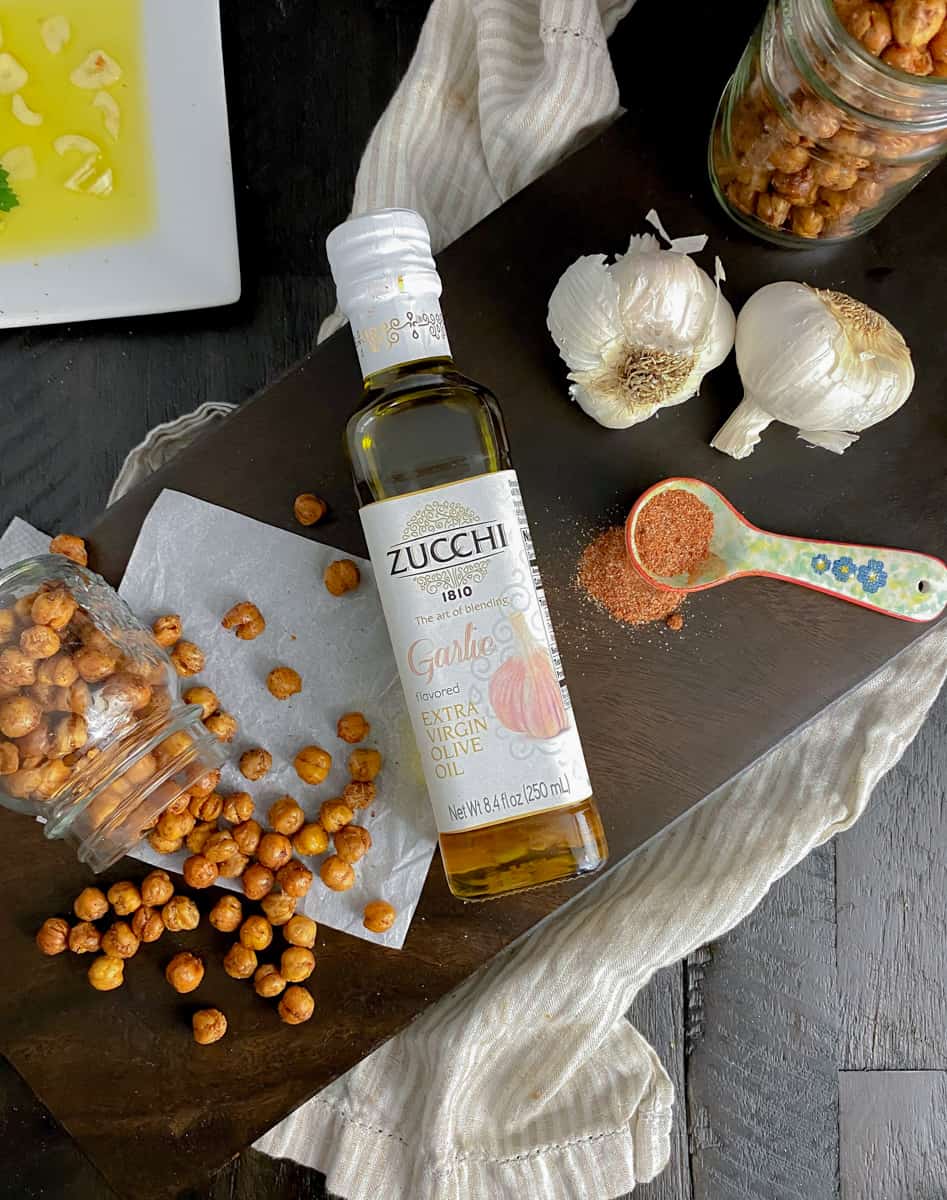 garlic spicy chickpeas on cutting board with bottle of garlic olive oil and spices