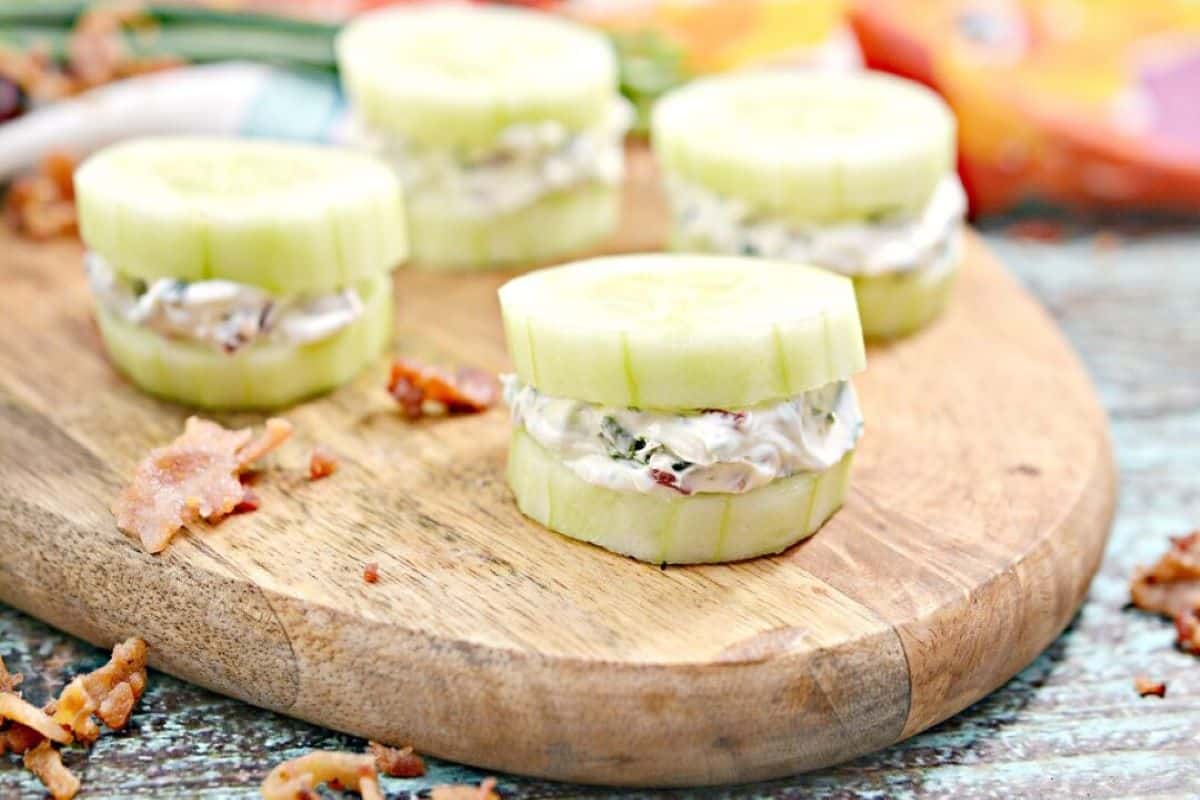 bacon and herb mini cucumber sandwich bites on a wooden cutting board.