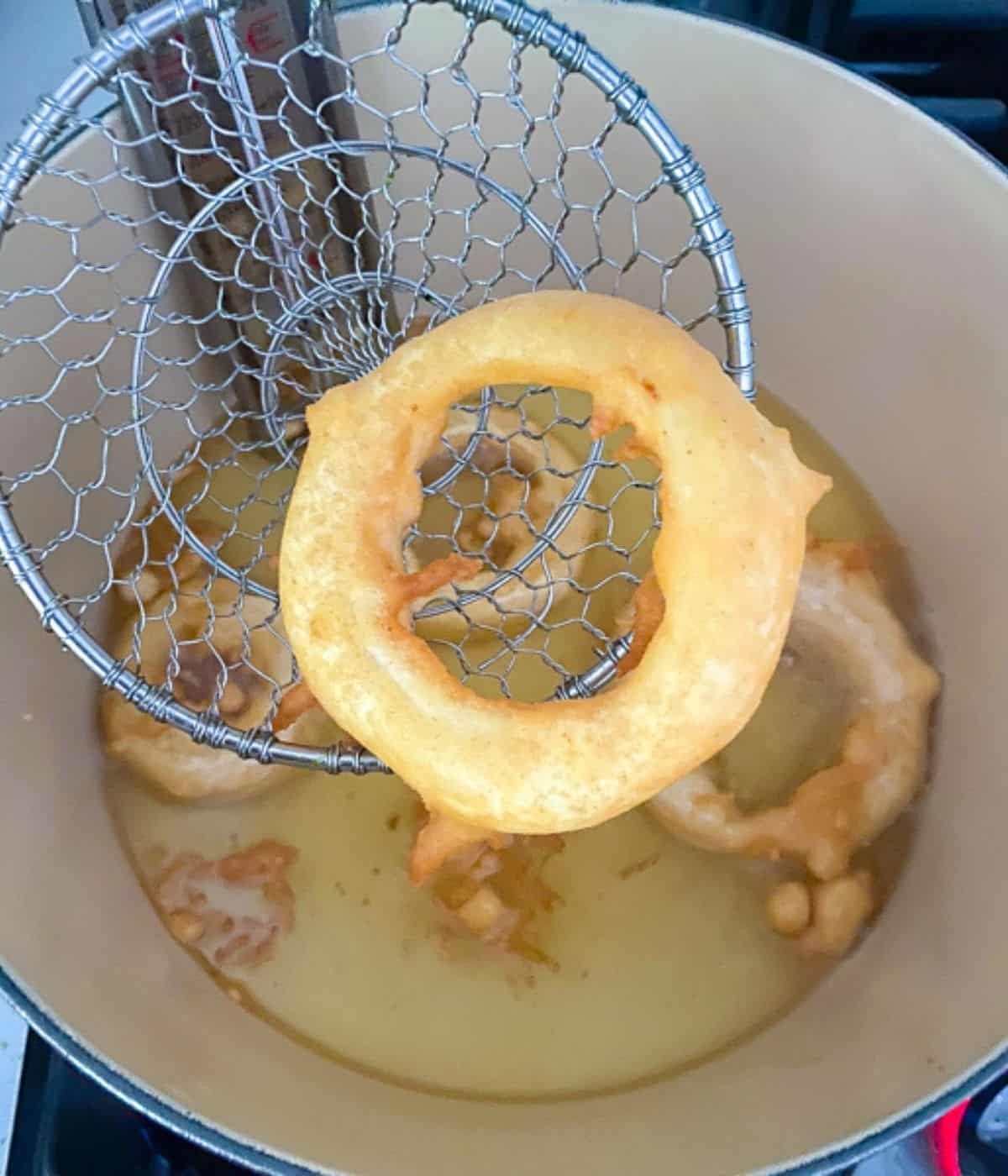 crispy beer battered onion ring coming out of the hot oil.