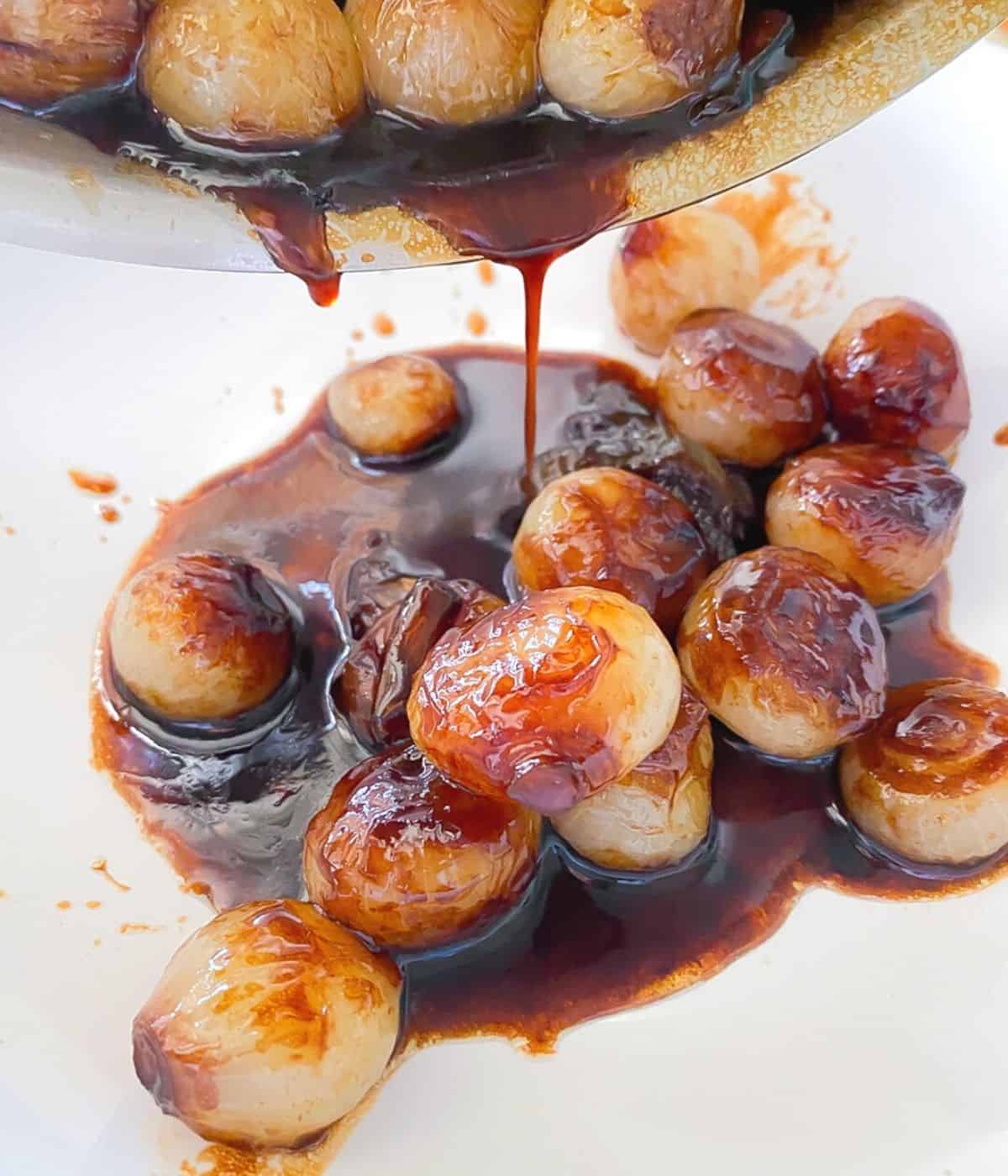 caramelized onions recipe with balsamic glaze being poured in a bowl.