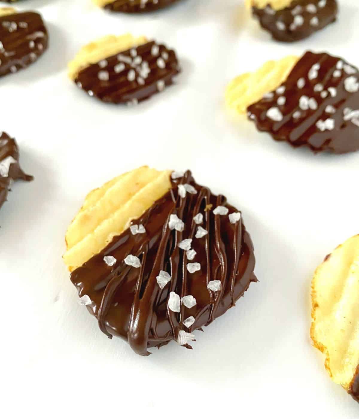 Chocolate covered potato chips on parchment paper with sea salt.