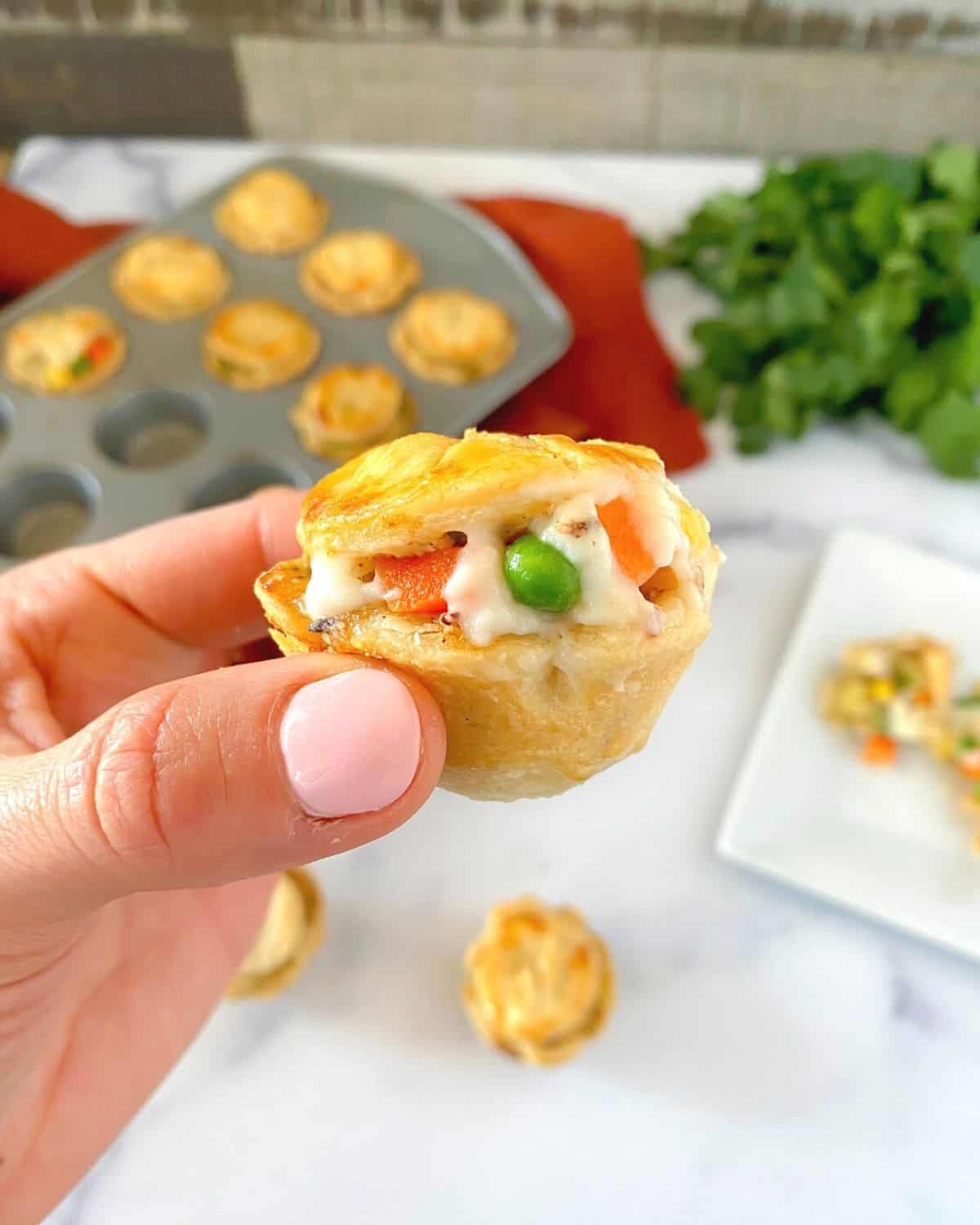 Mini chicken pot pie muffin being held in the air.