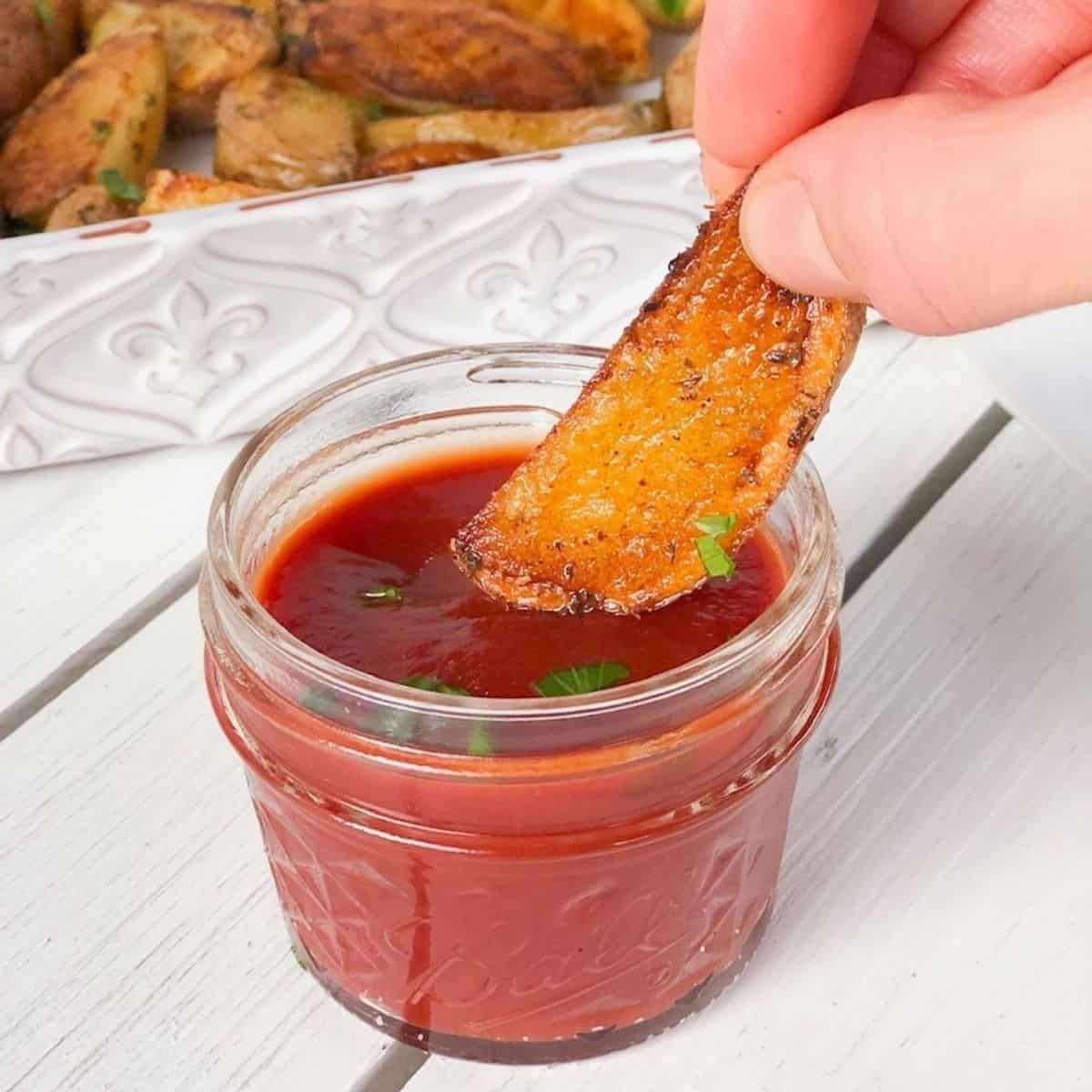 Croccante cuneo di patate al forno di essere immerso in ketchup.