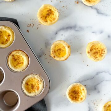 Mini egg custard tartlets in a muffin tin on table.