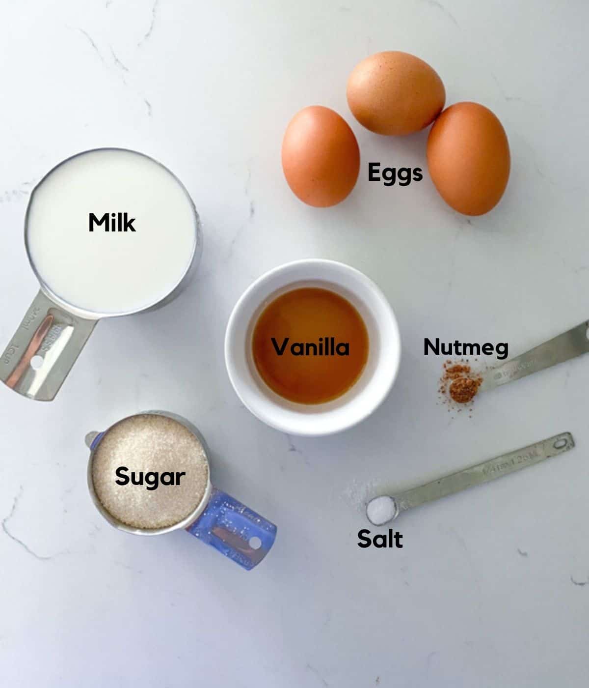 Egg custard tart ingredients on a table including vanilla, sugar, nutmeg, eggs, milk and salt.