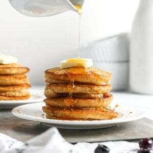 Silver dollar pancakes on a plate stacked with a skewer.